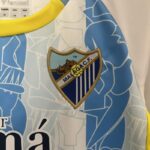 Conjunto Niño Málaga Primera Equipacion 2024-2025 logo